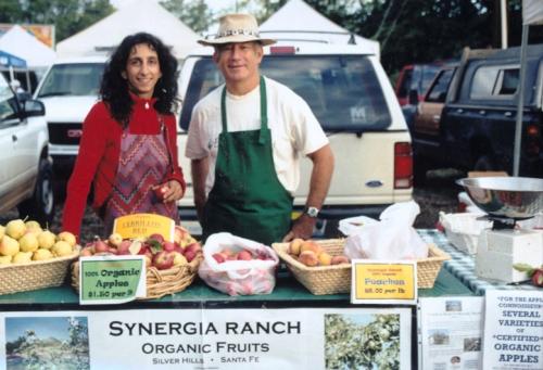 Thrity Vakil and Mark Nelson at Synergia Ranch booth, Santa Fe Farmer’s Market with organic fruits and vegetables, 2006.